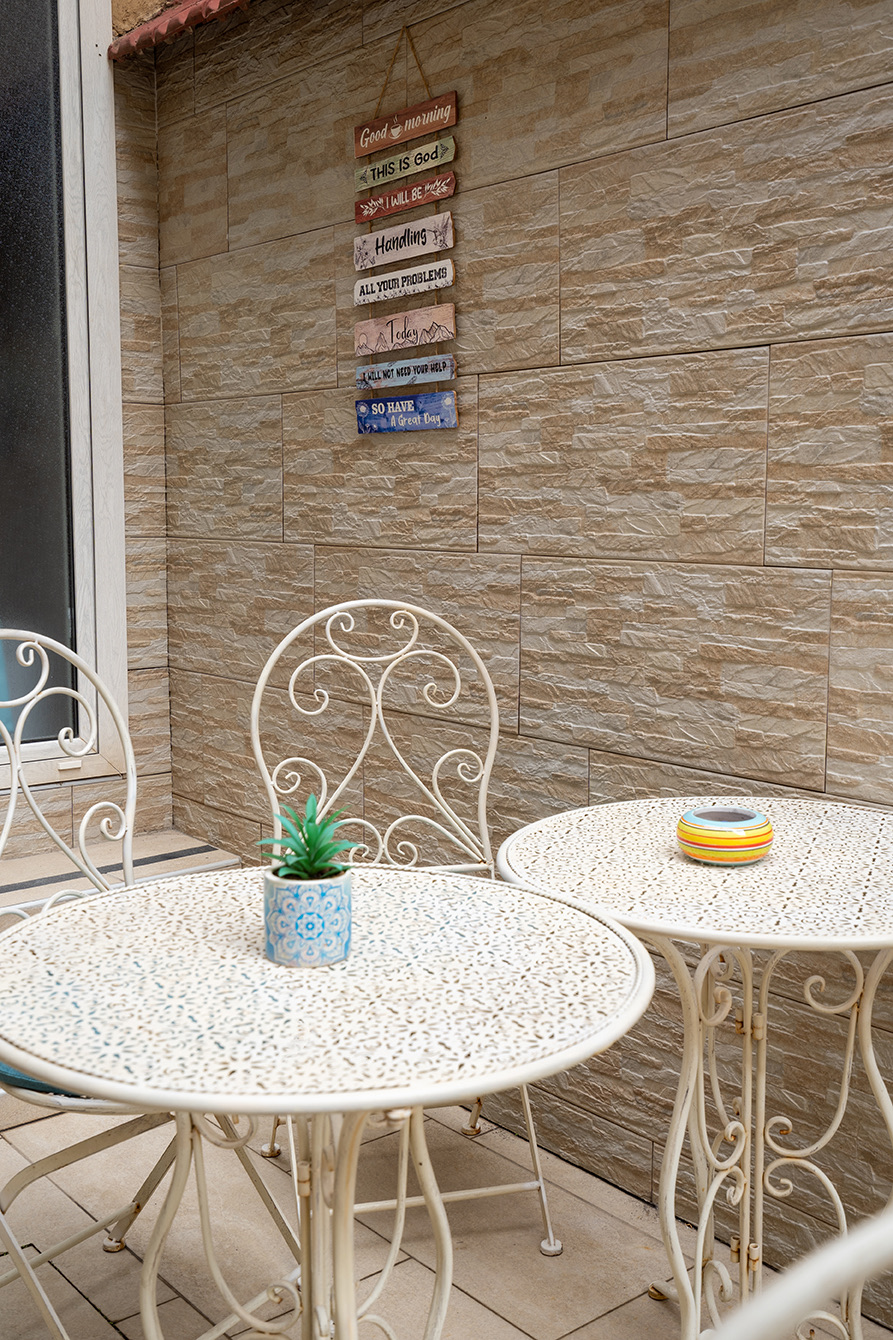 Weiße Eisentische und „Guten Morgen“-Schilder an der Terrassenwand