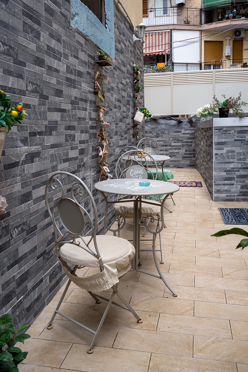 Eisentische und -stühle entlang der Steinmauer der Terrasse